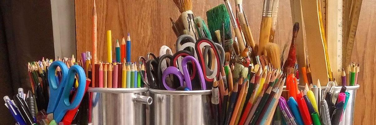 Paint brushes, rulers, colored pencils and scissors on a table